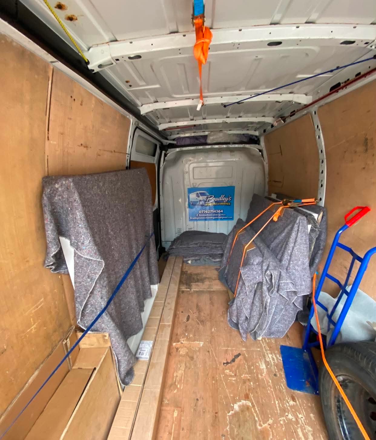 Inside Bradley's Removals & Logistics branded van with blankets and trolley
