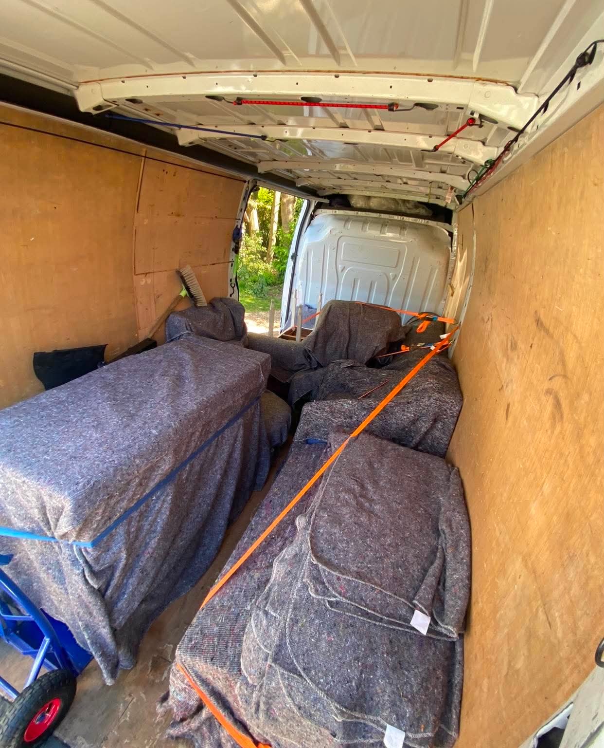 Furniture wrapped in blankets and strapped inside a removal van